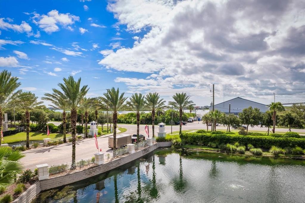 An elevated view of a pond, palm trees, a road, and a building under clouds — 1 RIVERWALK DRIVE UNIT 303, NEW SMYRNA BEACH, FL