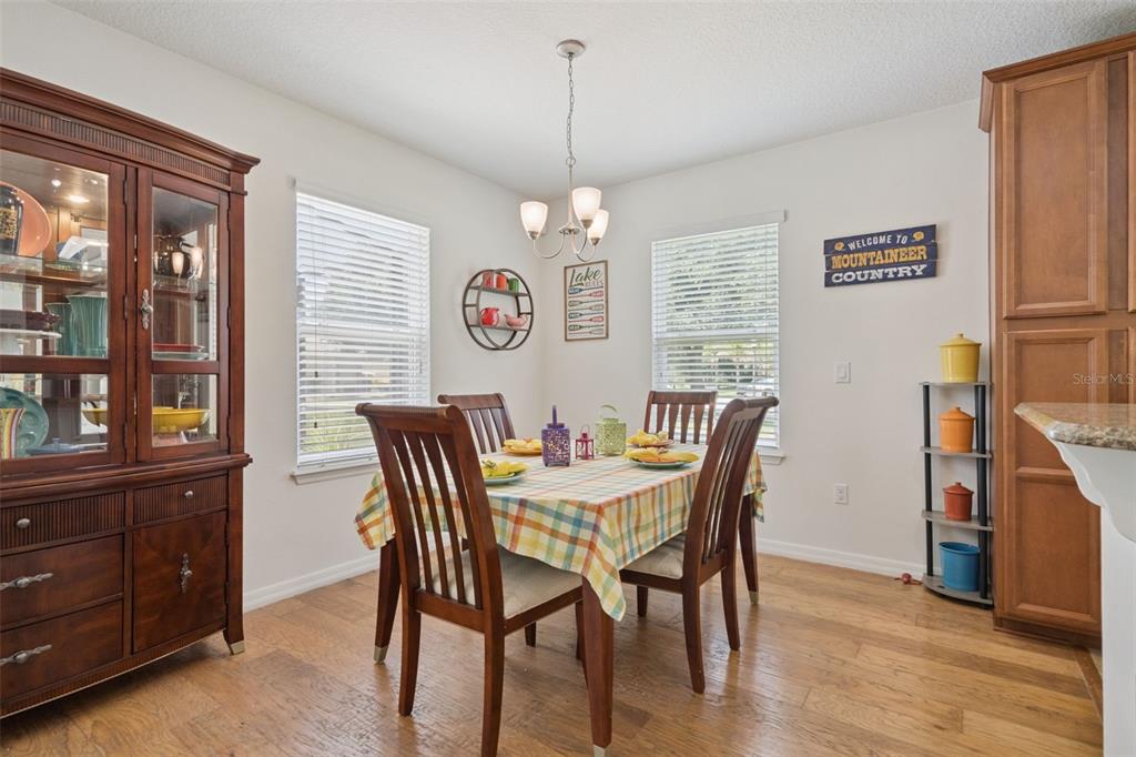 A dining room features a wooden table with a plaid tablecloth, chairs, and a hutch — 9026 PAOLOS PLACE, KISSIMMEE, FL