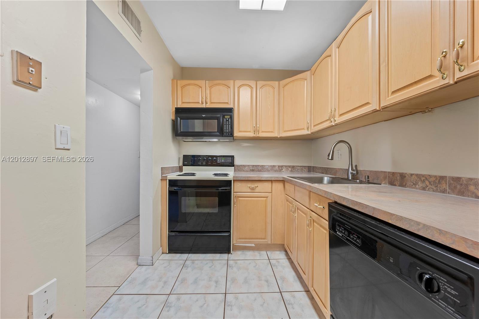 A kitchen features light wood cabinets, black appliances, a tiled floor, and laminate countertops — 7829 Miller Dr # B205, Miami FL 33155, MIAMI, FL