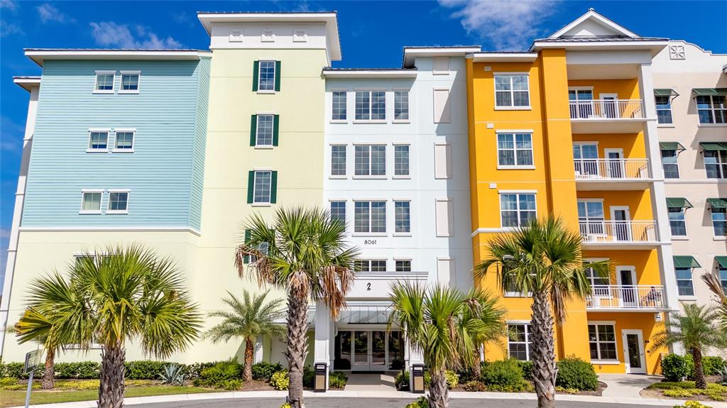 A multi-story apartment building features colorful blue, yellow, and white exterior walls with balconies — 8061 VACATION AVENUE UNIT 114, KISSIMMEE, FL