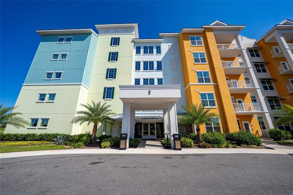 A multi-story apartment building with a covered entrance and colorful exterior facades — 8061 VACATION AVENUE UNIT 114, KISSIMMEE, FL