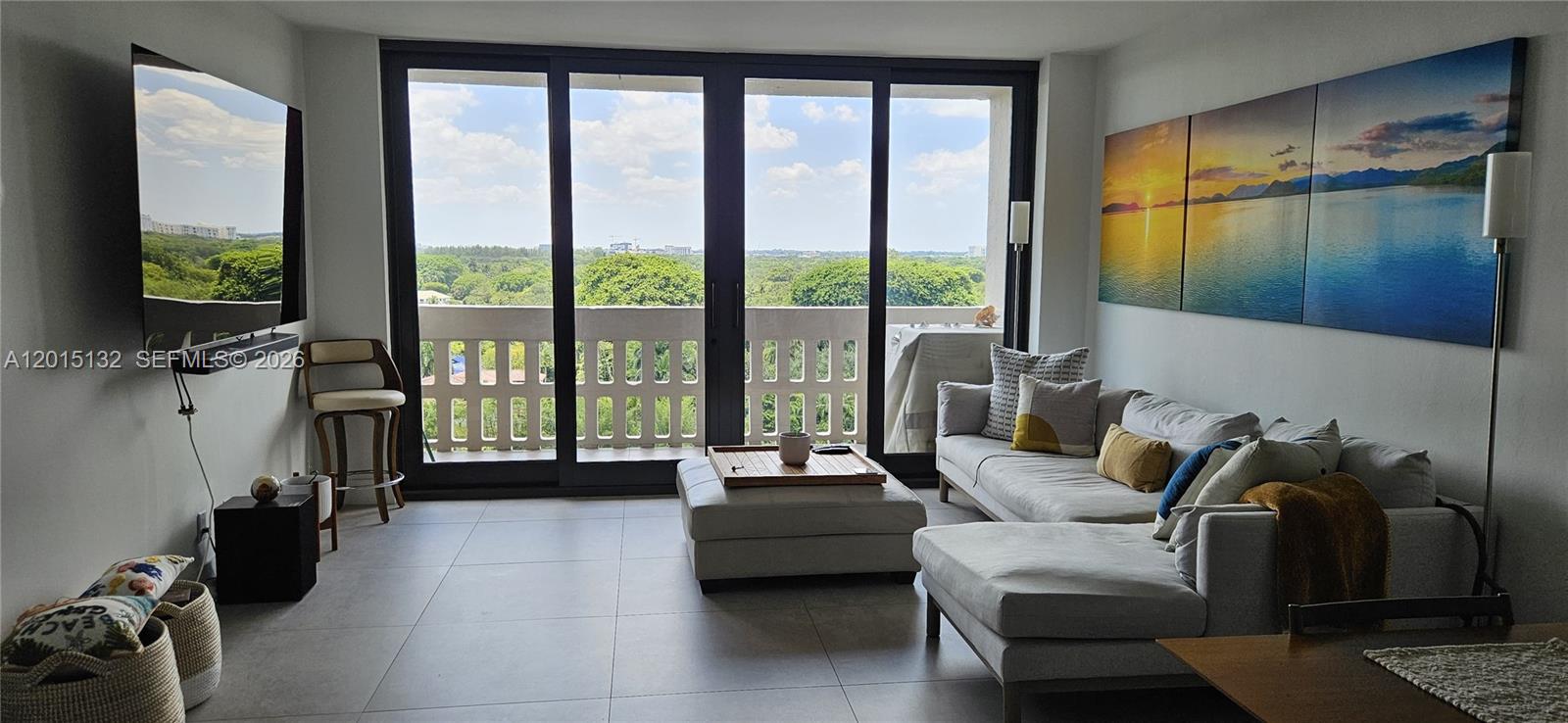 A living room features a sectional sofa, a large television, and sliding glass balcony doors — 90 Edgewater Dr # 1219, Coral Gables FL 33133, CORAL GABLES, FL