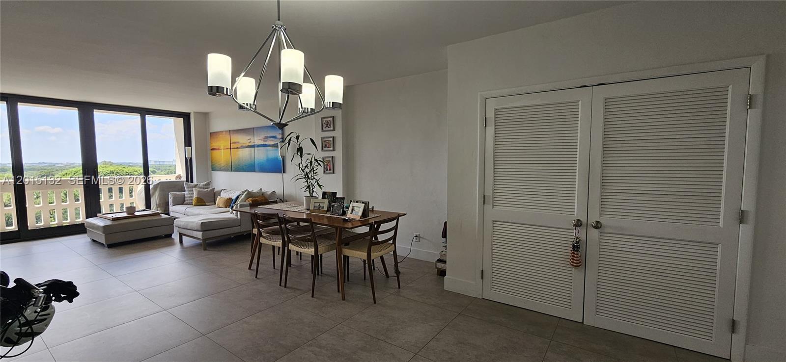 A dining area with a chandelier and table sits adjacent to a living room — 90 Edgewater Dr # 1219, Coral Gables FL 33133, CORAL GABLES, FL
