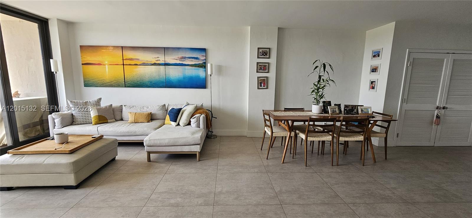 A living and dining area features a sectional sofa, wooden table, and large wall art — 90 Edgewater Dr # 1219, Coral Gables FL 33133, CORAL GABLES, FL