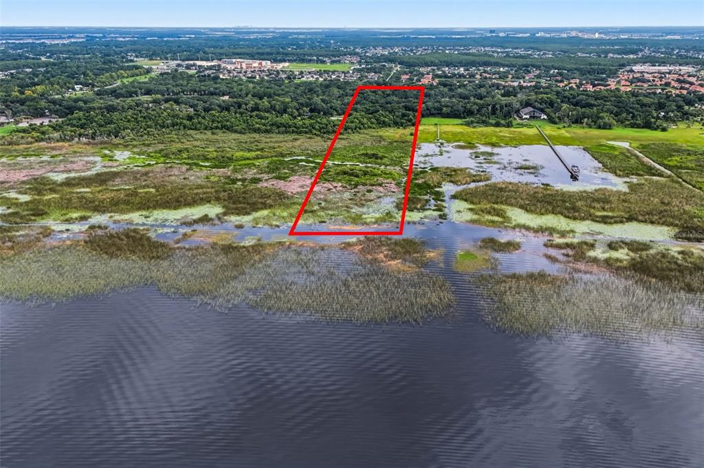 An aerial view shows a red-outlined plot of land extending from a lake into woods — 2794 HOLIDAY WOODS DRIVE, KISSIMMEE, FL