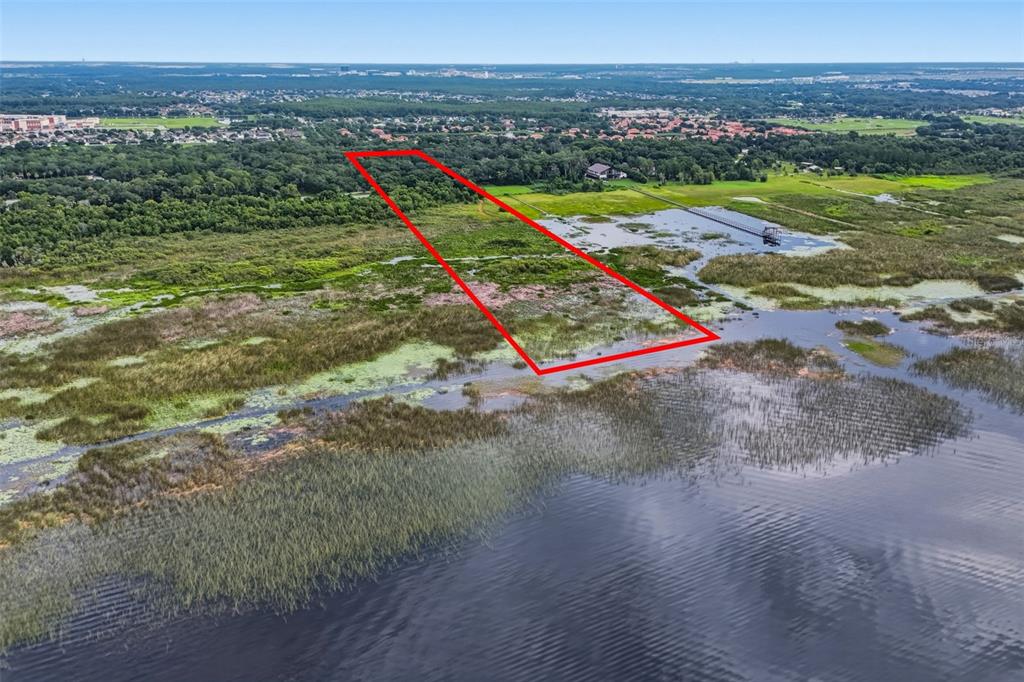 An aerial view shows a rectangular plot of land outlined in red near a lake — 2794 HOLIDAY WOODS DRIVE, KISSIMMEE, FL