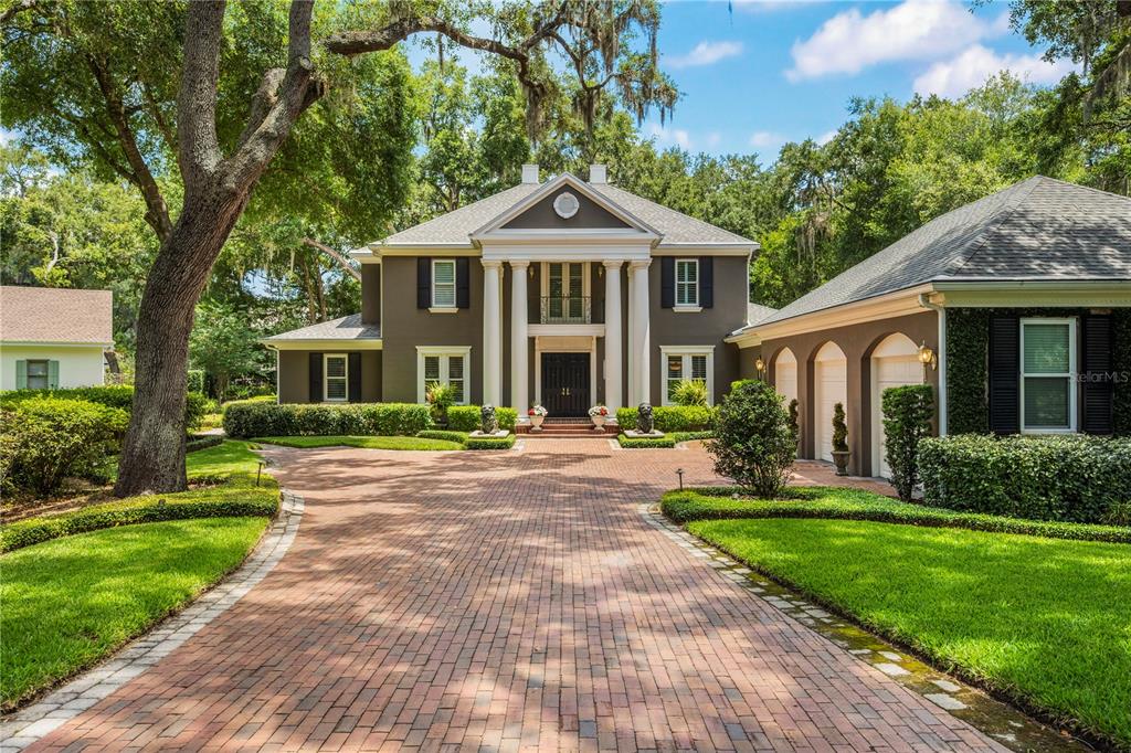 A two-story house with a brick driveway, white columns, and a dark exterior — 5009 PLEASURE ISLAND ROAD, BELLE ISLE, FL