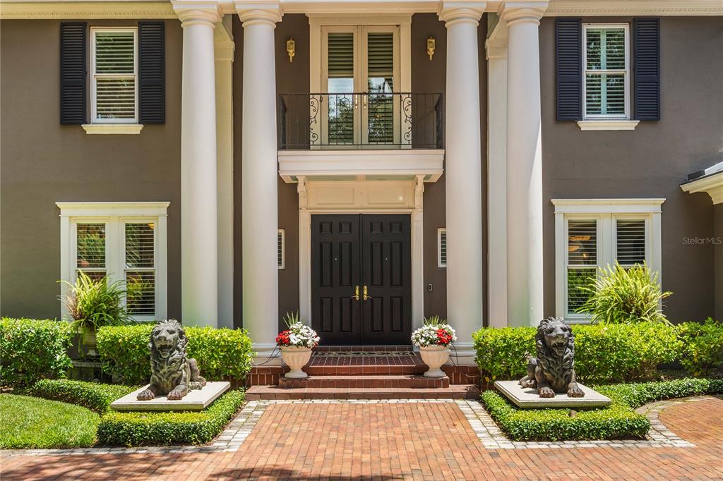 The front entrance of a house features large white columns, lion statues, and double doors — 5009 PLEASURE ISLAND ROAD, BELLE ISLE, FL