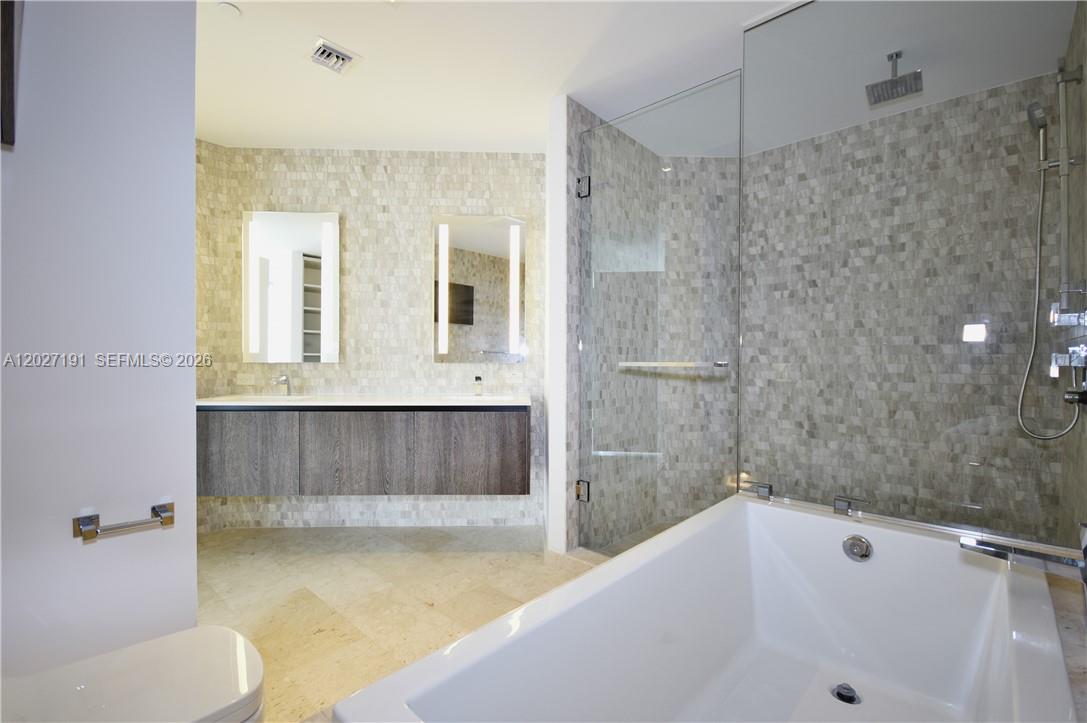 A modern bathroom features a floating double vanity, a glass-enclosed shower, and a soaking tub — 68 SE 6th St # 2812, Miami FL 33131, MIAMI, FL