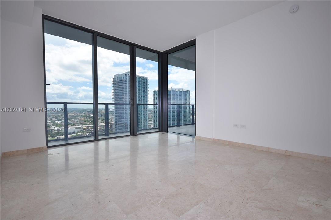 An empty room features light-colored marble floors, white walls, and floor-to-ceiling windows with city views — 68 SE 6th St # 2812, Miami FL 33131, MIAMI, FL