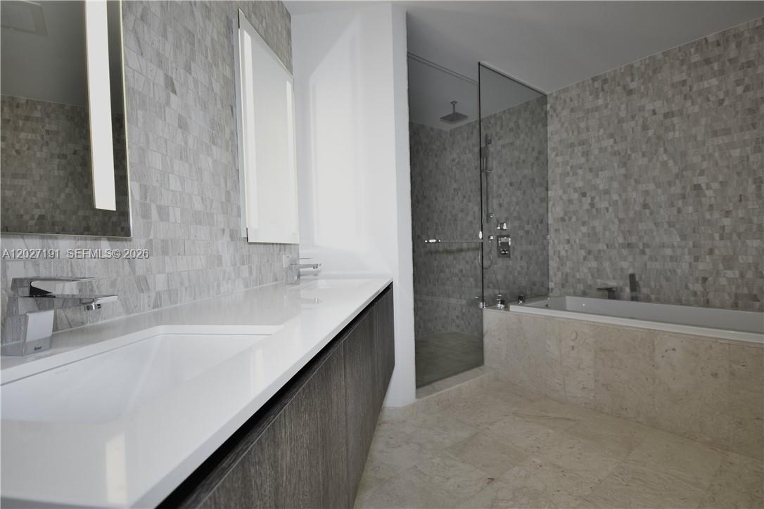 A modern bathroom features a double vanity, a glass-enclosed shower, and a built-in bathtub — 68 SE 6th St # 2812, Miami FL 33131, MIAMI, FL