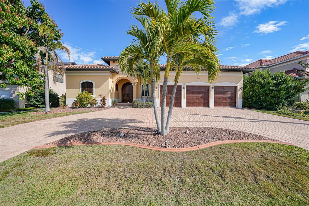 A single-story house with a three-car garage, a palm tree, and a paved driveway — 166 HIBISCUS DRIVE, PUNTA GORDA, FL
