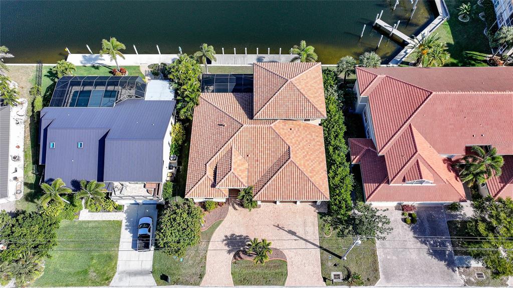 An aerial view shows three waterfront houses with tiled roofs and a shared canal — 166 HIBISCUS DRIVE, PUNTA GORDA, FL