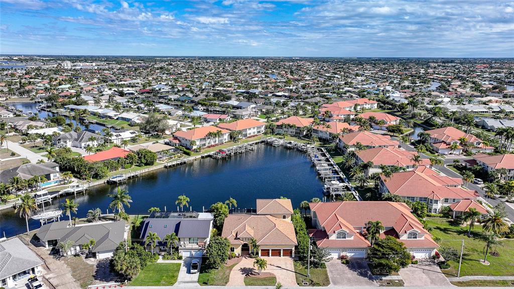 An aerial view shows waterfront homes with tiled roofs surrounding a canal with boat docks — 166 HIBISCUS DRIVE, PUNTA GORDA, FL