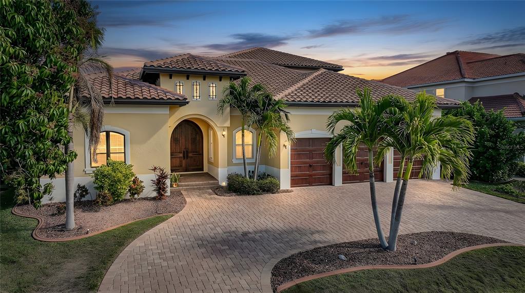 A yellow stucco house with a tiled roof, arched entryway, and a paved driveway — 166 HIBISCUS DRIVE, PUNTA GORDA, FL