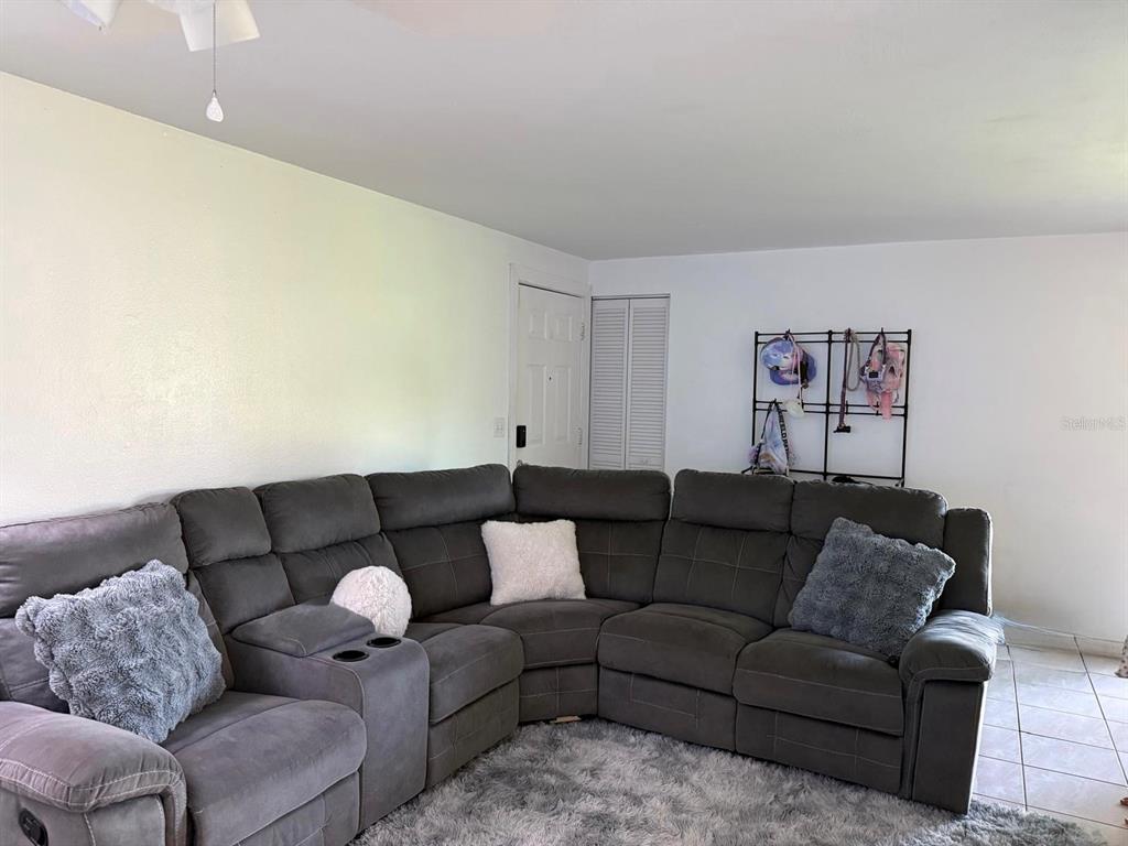 A living room features a large gray sectional sofa on a shag rug — 5026 WATER OAK DRIVE UNIT 114, BRADENTON, FL