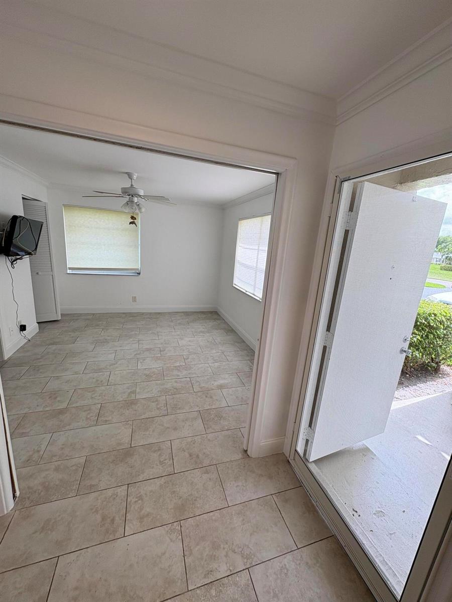 An open doorway leads to a tiled room with a ceiling fan and two windows — 1020 Silk Oak Terrace # 104, Delray Beach FL 33445, DELRAY BEACH, FL