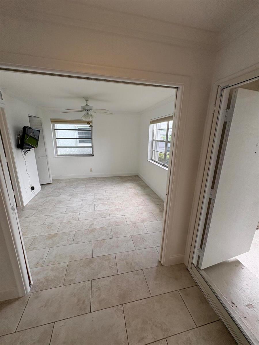 A room with light-colored tile flooring, white walls, a ceiling fan, and two windows — 1020 Silk Oak Terrace # 104, Delray Beach FL 33445, DELRAY BEACH, FL