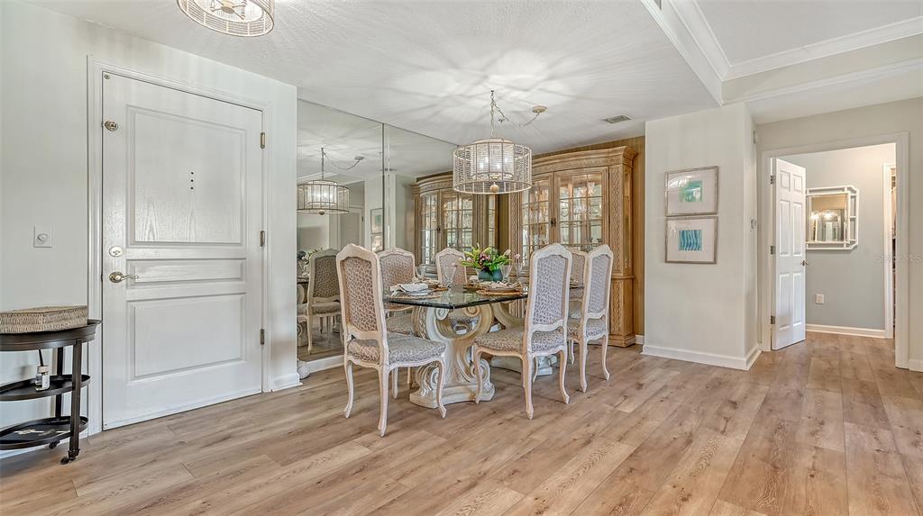 A dining room with a glass table, upholstered chairs, a mirrored wall, and wood flooring — 750 N TAMIAMI TRAIL UNIT 304, SARASOTA, FL
