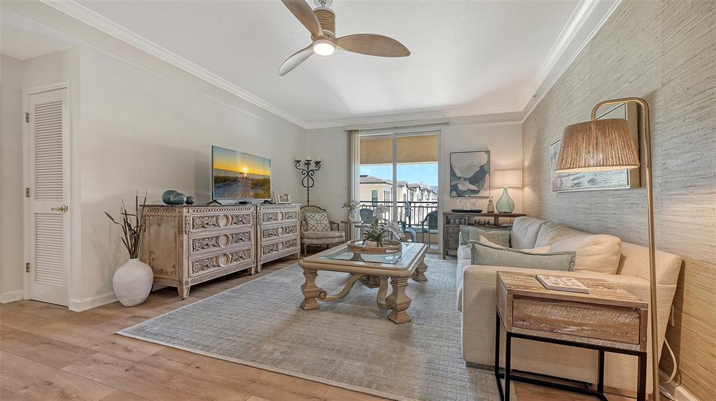 A living room features a beige sofa, wooden coffee table, television console, and ceiling fan — 750 N TAMIAMI TRAIL UNIT 304, SARASOTA, FL