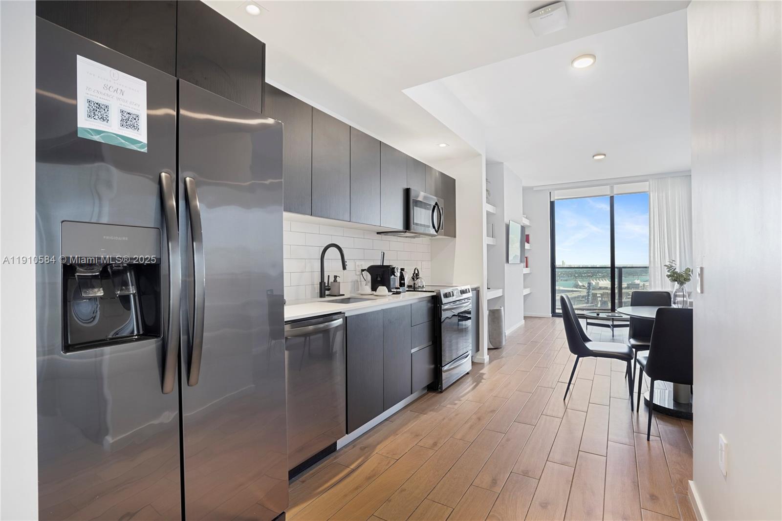 A modern kitchen features dark cabinetry, stainless steel appliances, and wood-look flooring near a balcony — 398 NE 5th St # 1811, Miami FL 33132, MIAMI, FL