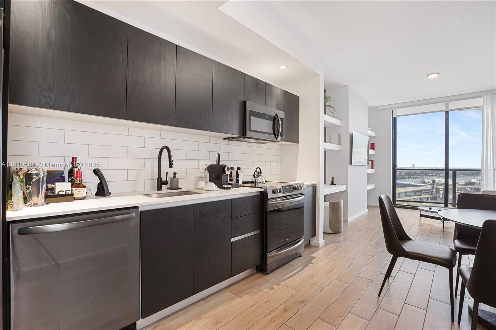 A modern kitchen features dark wood cabinetry, white subway tile backsplash, and stainless steel appliances — 398 NE 5th St # 1811, Miami FL 33132, MIAMI, FL