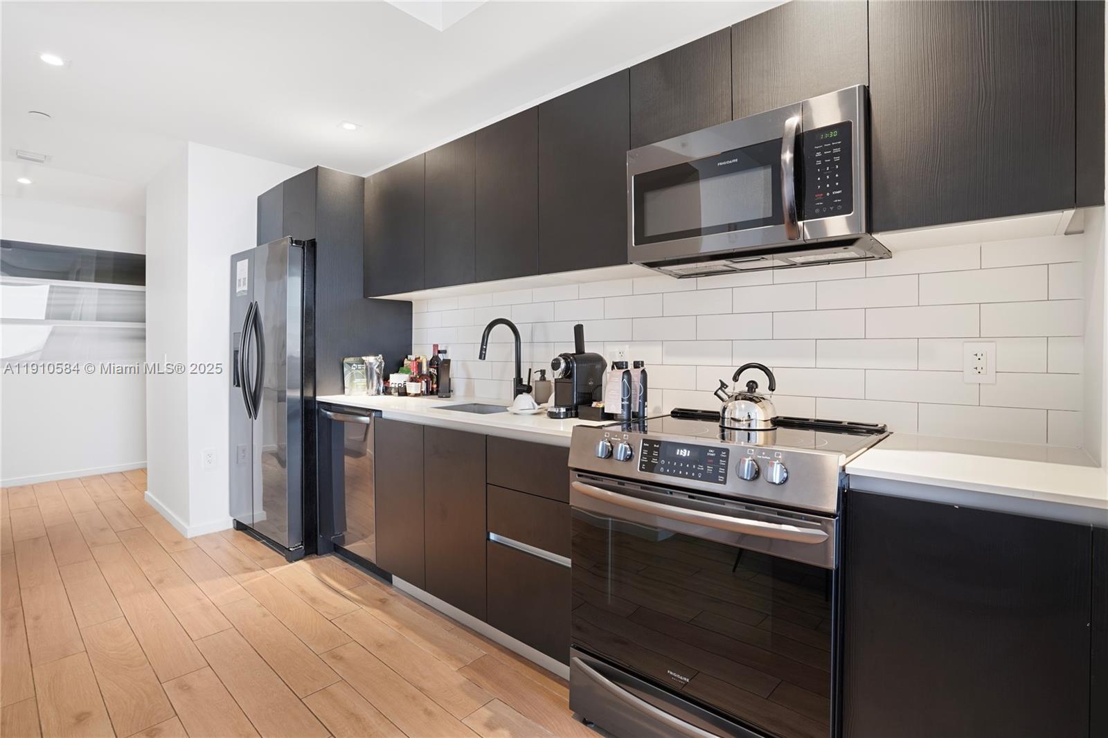 A modern kitchen features dark wood cabinetry, stainless steel appliances, and a white subway tile backsplash — 398 NE 5th St # 1811, Miami FL 33132, MIAMI, FL