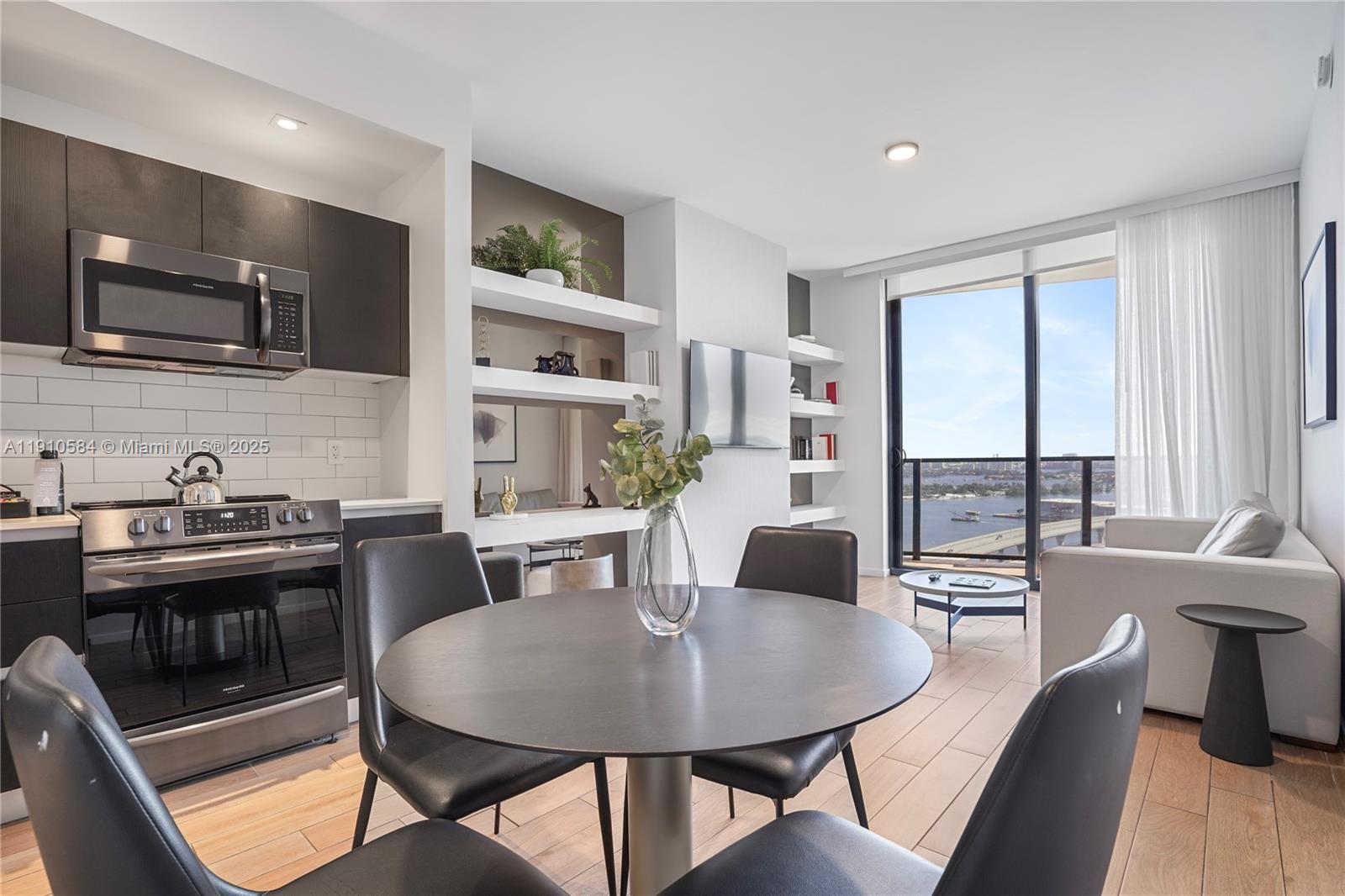 A modern apartment features an open kitchen, dining area, and living space with balcony views — 398 NE 5th St # 1811, Miami FL 33132, MIAMI, FL