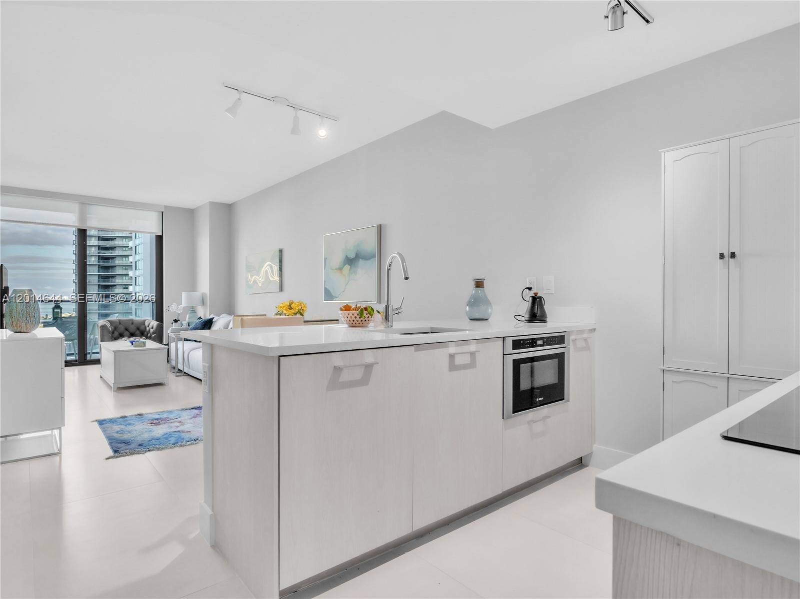 A modern kitchen island with a built-in microwave sits in an open-concept living space — 501 NE 31st St # 1105, Miami FL 33137, MIAMI, FL