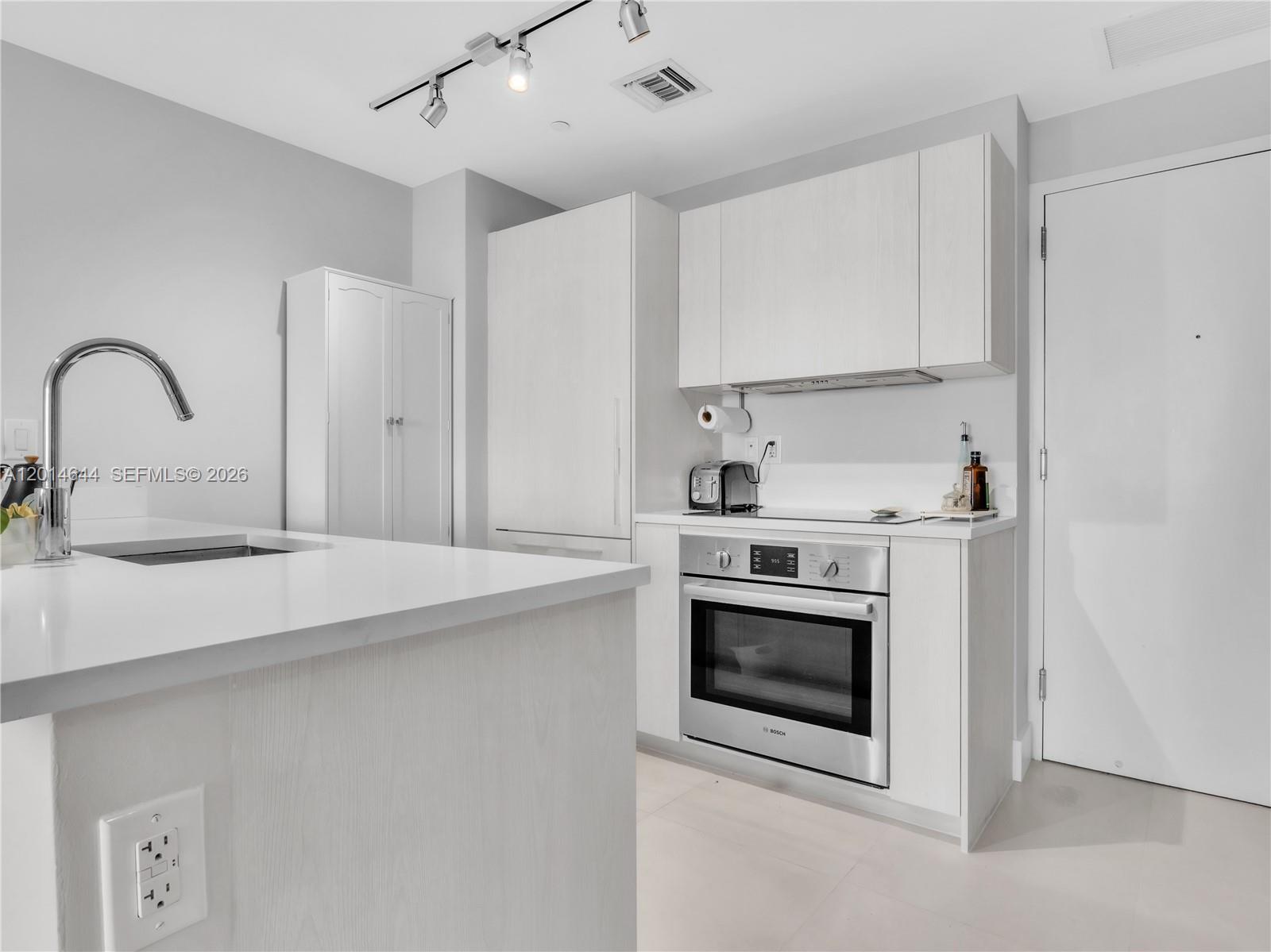 A modern kitchen features white cabinetry, stainless steel appliances, and a white countertop island — 501 NE 31st St # 1105, Miami FL 33137, MIAMI, FL