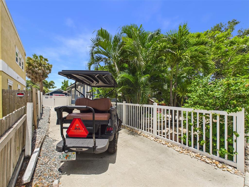 A golf cart is parked on a concrete driveway next to a white fence — 616 15TH STREET N, ST PETERSBURG, FL