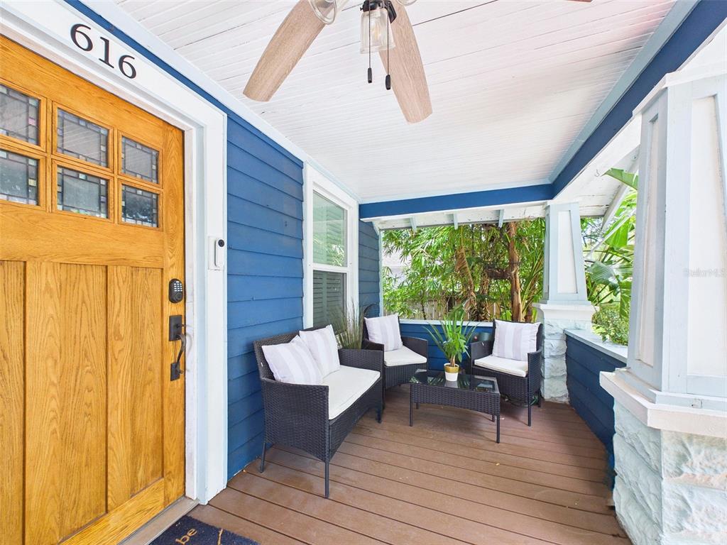 A covered front porch features blue siding, a wooden door, and outdoor wicker furniture — 616 15TH STREET N, ST PETERSBURG, FL