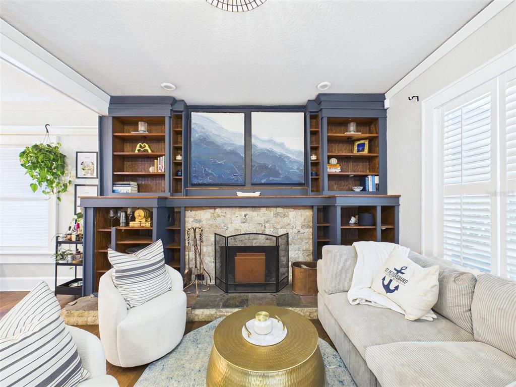 A living room features a stone fireplace flanked by dark blue built-in shelving units — 616 15TH STREET N, ST PETERSBURG, FL