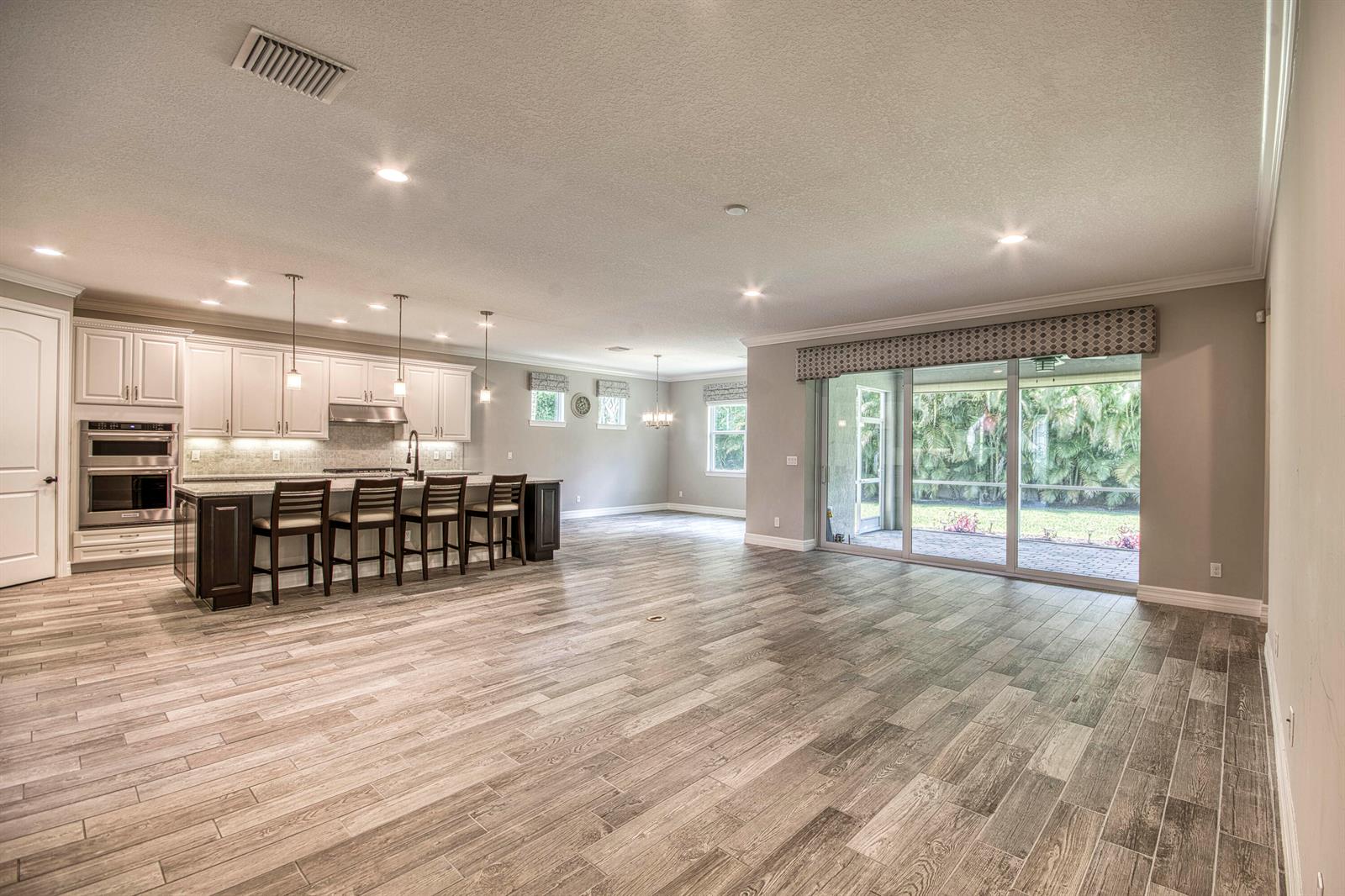 A kitchen with a large island and bar seating opens to a spacious living area — 134 Shores Pointe Drive, Jupiter FL 33458, JUPITER, FL