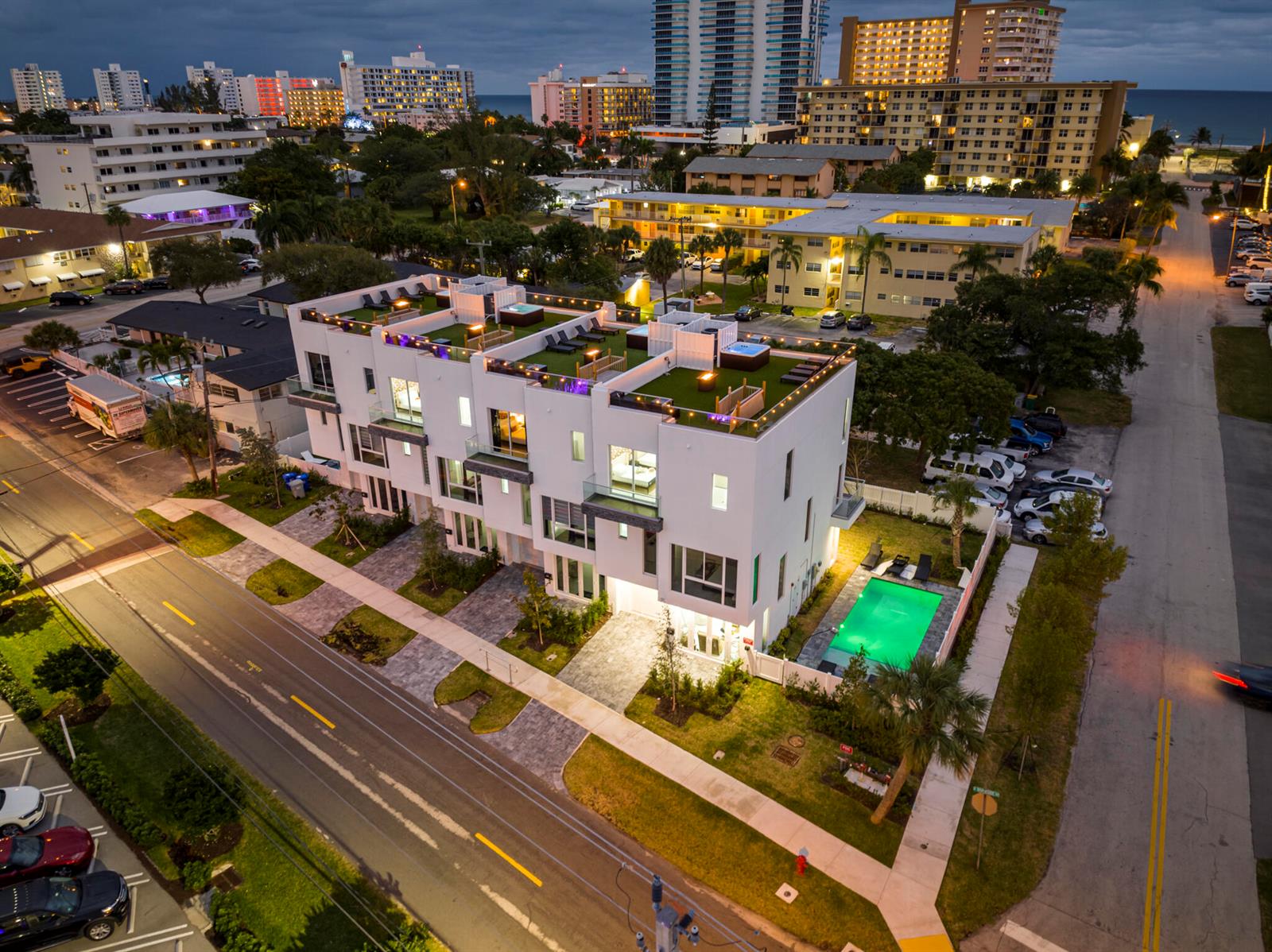 An aerial view of a modern white townhouse complex featuring rooftop decks and a swimming pool — 1006 N Riverside Drive, Pompano Beach FL 33062, POMPANO BEACH, FL