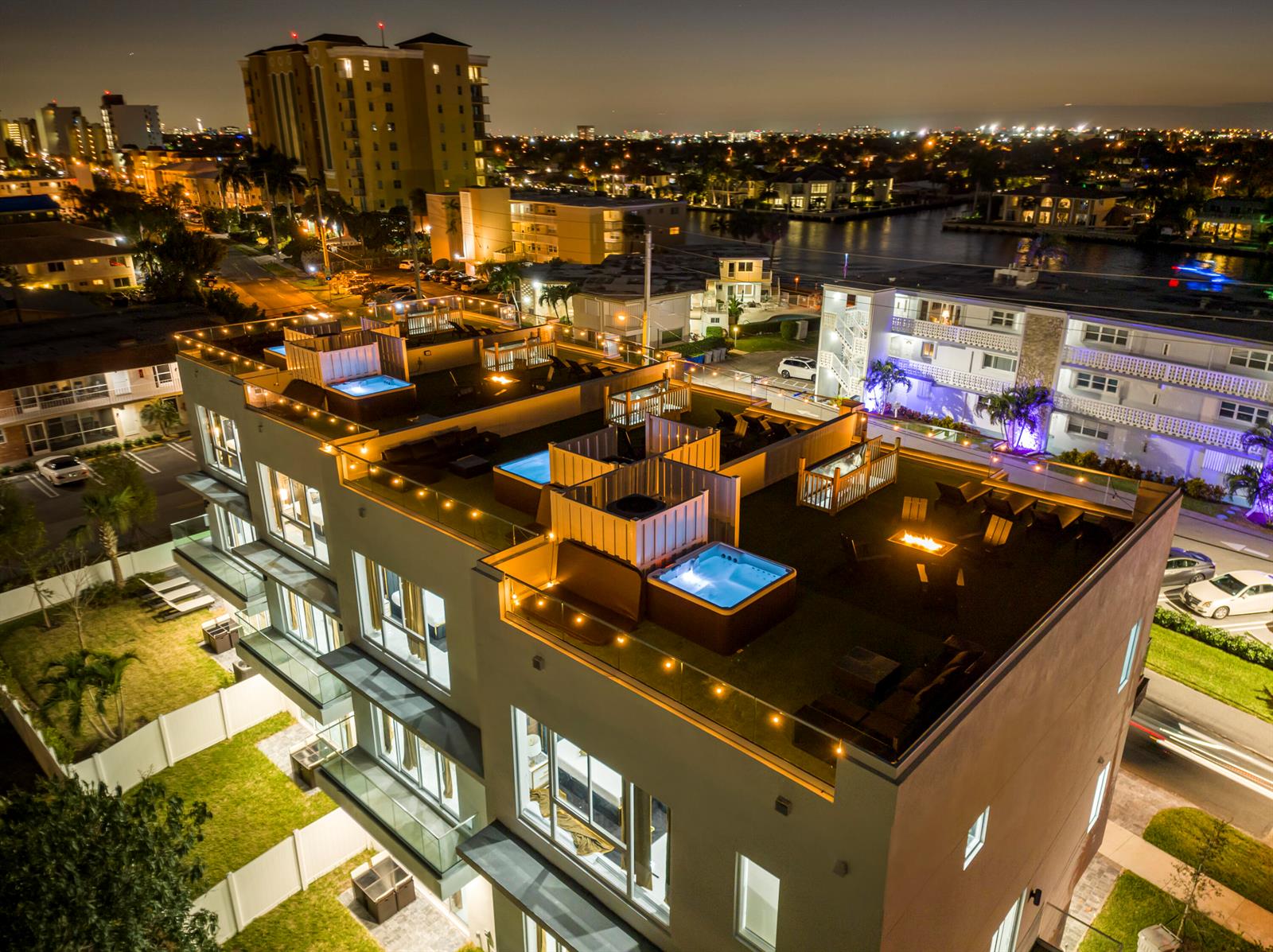 An aerial night view of a modern apartment building featuring rooftop hot tubs and fire pits — 1006 N Riverside Drive, Pompano Beach FL 33062, POMPANO BEACH, FL