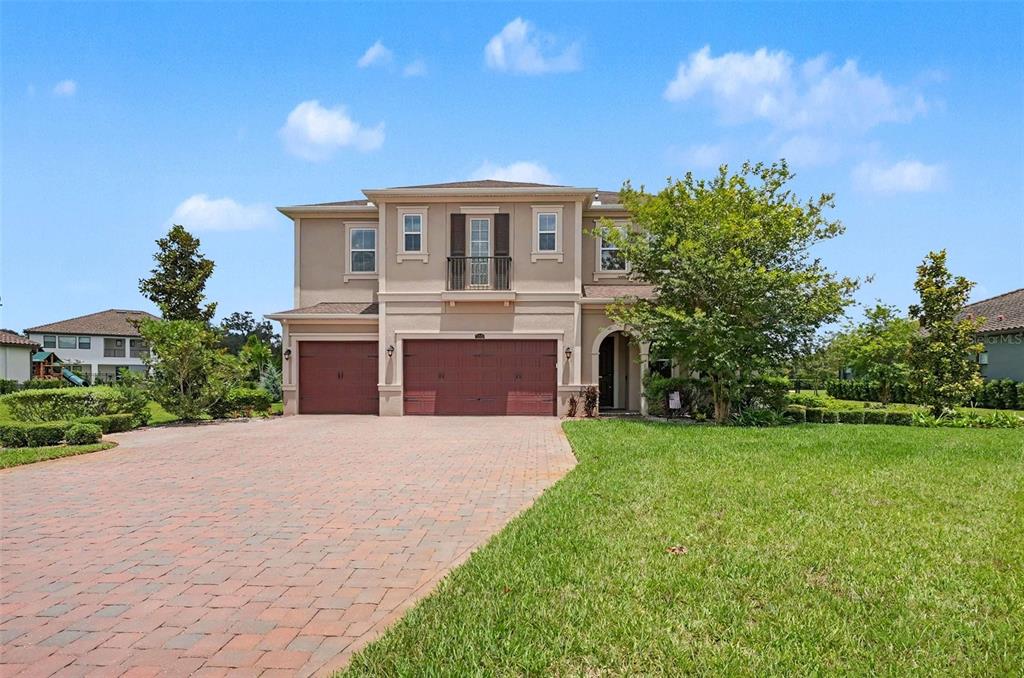 A two-story suburban house with a three-car garage and a paved driveway — 17823 DAISY FARM DRIVE, LUTZ, FL