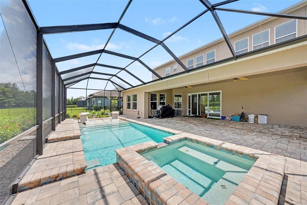 A spacious living room with a sectional sofa, two armchairs, and a view of a pool — 17823 DAISY FARM DRIVE, LUTZ, FL