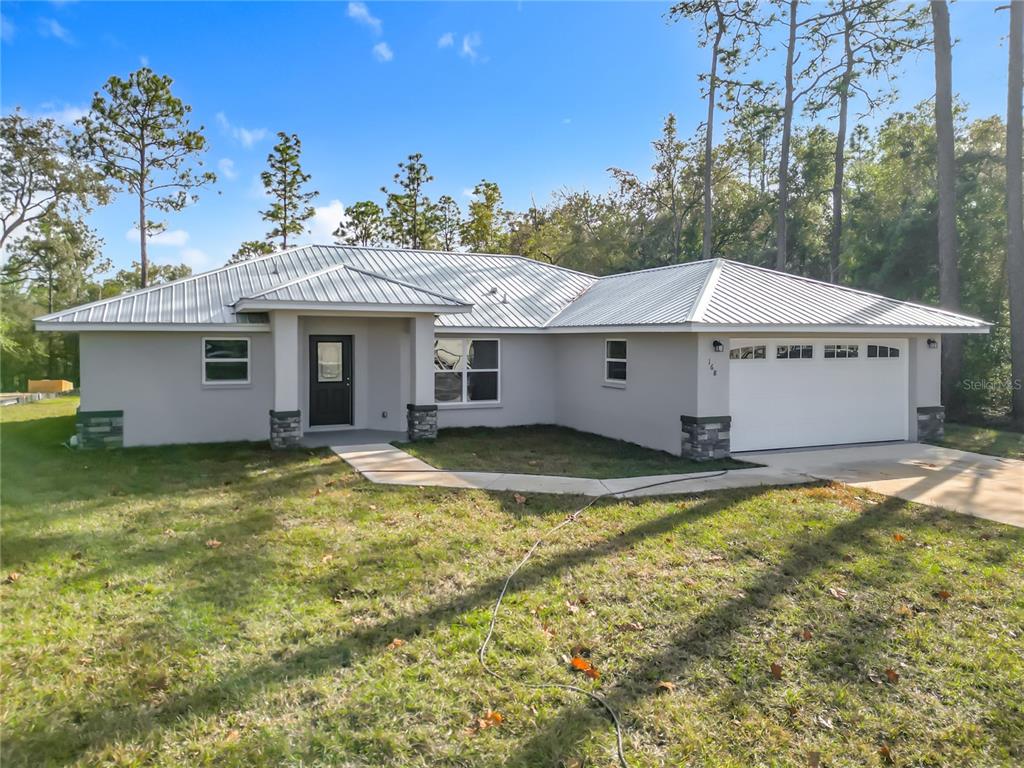A single-story house with a metal roof, gray stucco exterior, and a two-car garage — 168 W CITRUS SPRINGS BOULEVARD, CITRUS SPRINGS, FL