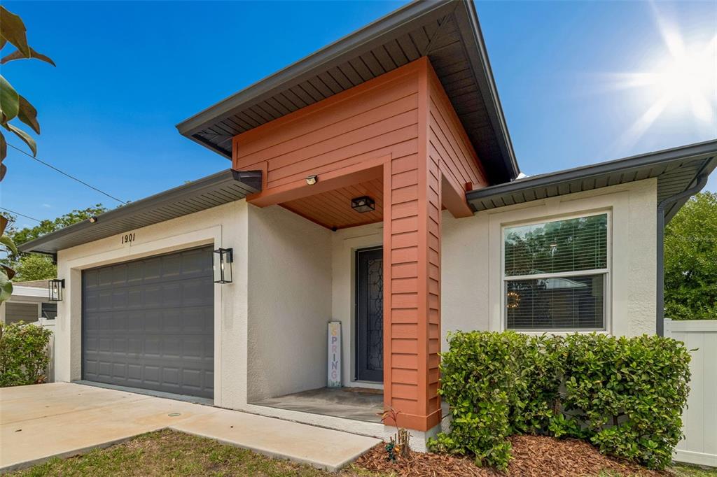 The exterior of a modern house features a garage, a covered entryway, and a front window — 1901 W CLUSTER AVENUE, TAMPA, FL