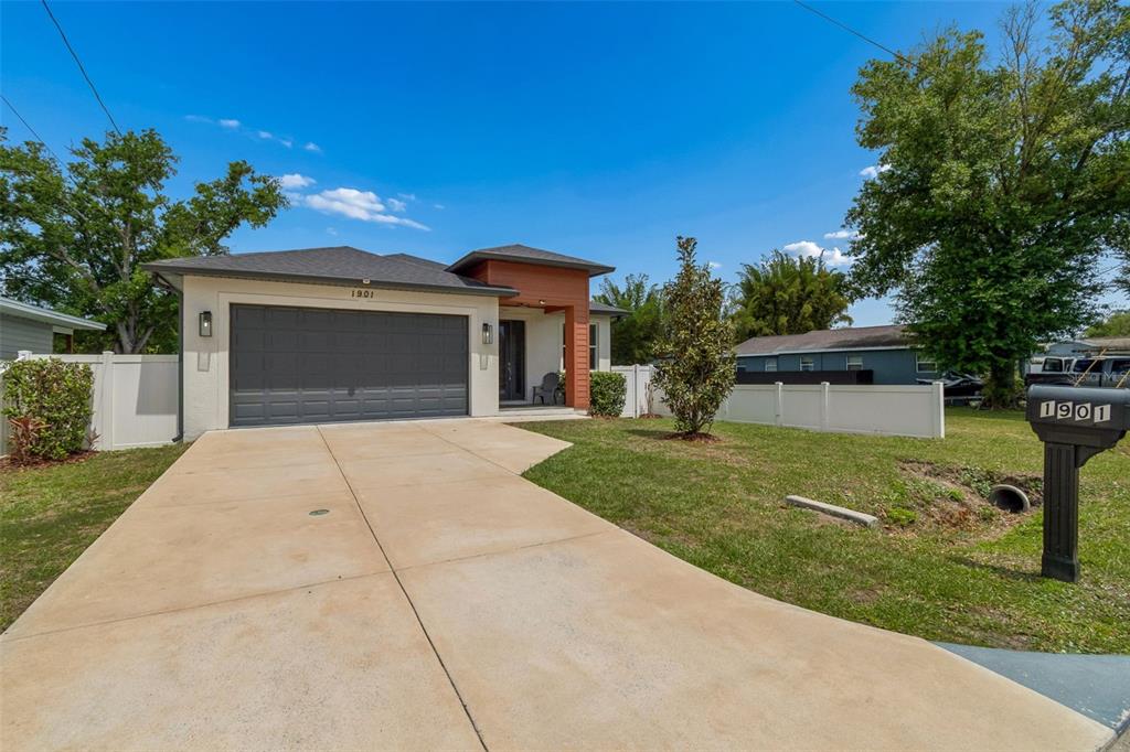A single-story house with a two-car garage, a concrete driveway, and a white vinyl fence — 1901 W CLUSTER AVENUE, TAMPA, FL
