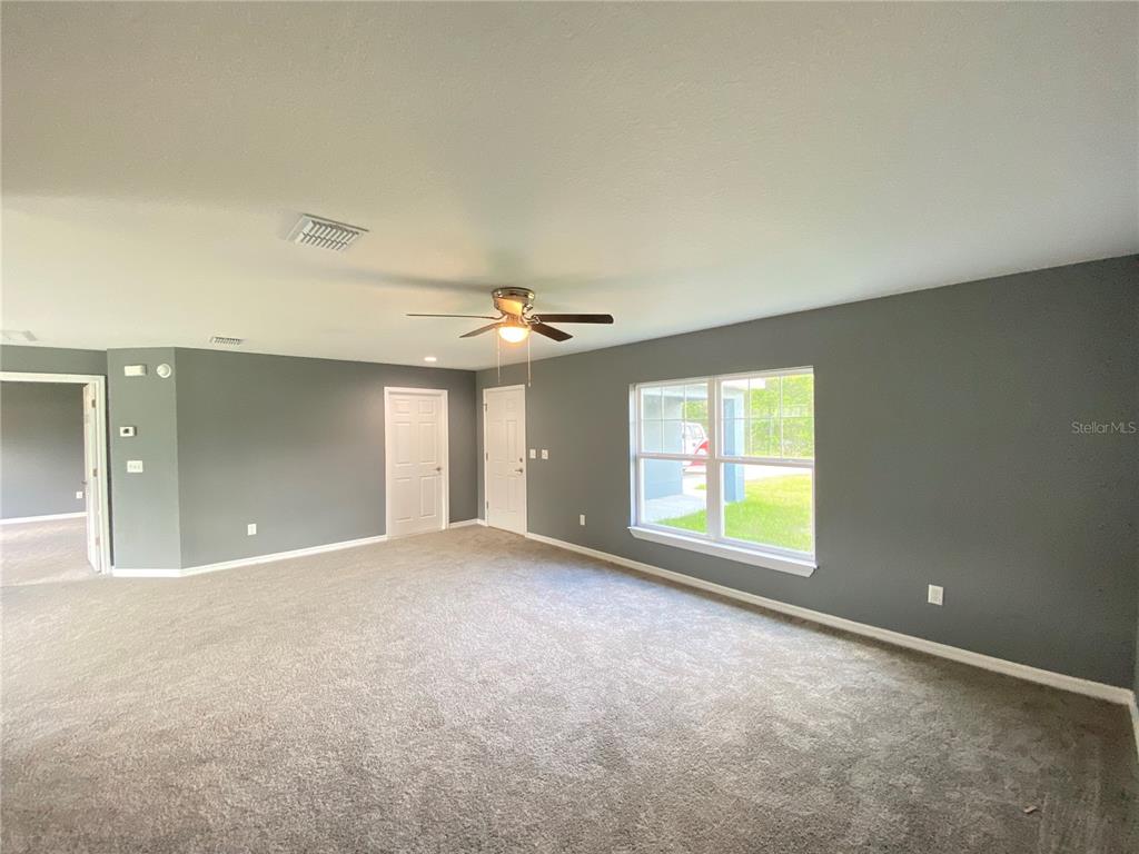 A spacious room with gray walls, carpeted flooring, a ceiling fan, and a window — 4004 SW 138TH PLACE, OCALA, FL