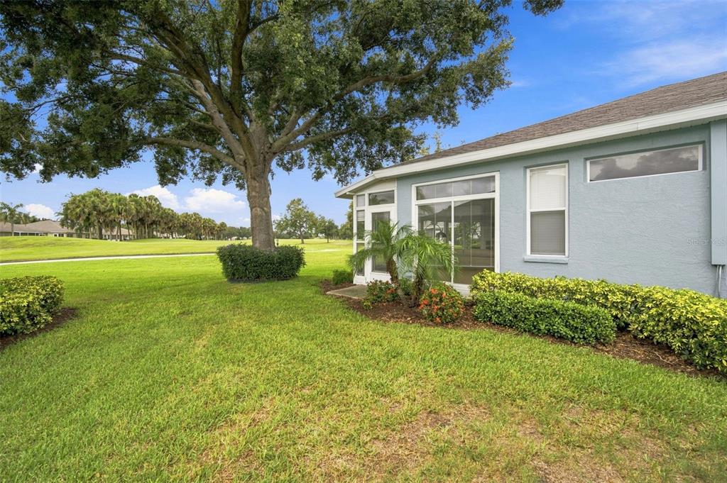 The exterior of a light blue house features a large tree and a grassy lawn — 2102 ACADIA GREENS DRIVE UNIT 2102, SUN CITY CENTER, FL