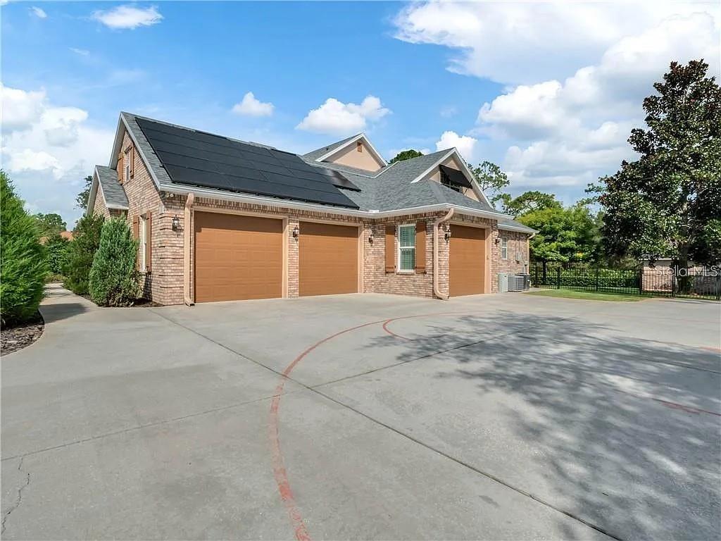 A brick house features a three-car garage and solar panels on the roof — 2660 WINNEMISSETT OAKS DRIVE, DELAND, FL