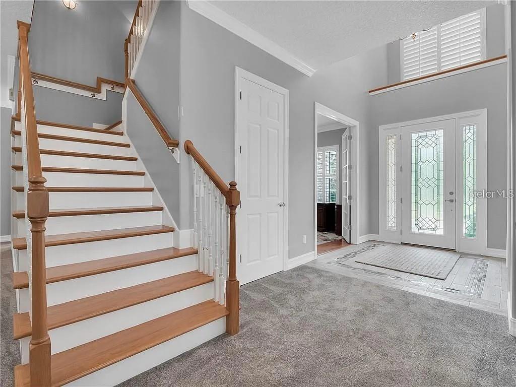 A foyer features a carpeted staircase with wooden railings, a white door, and a front entrance — 2660 WINNEMISSETT OAKS DRIVE, DELAND, FL