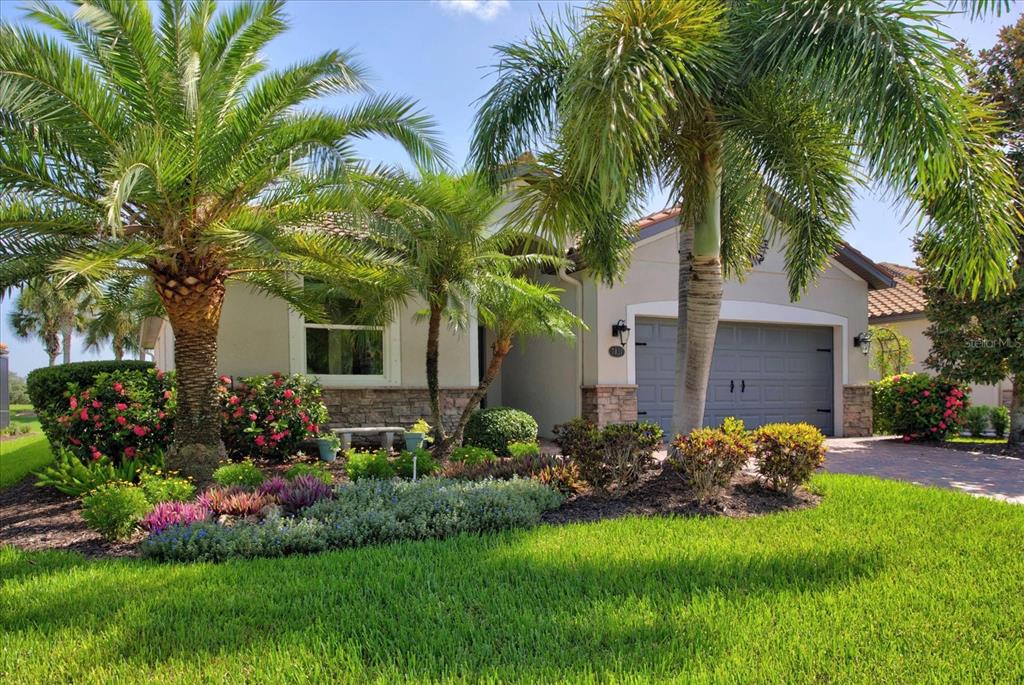 A single-story house with a gray garage, stone accents, and palm trees in the front yard — 7031 QUIET CREEK DRIVE, BRADENTON, FL