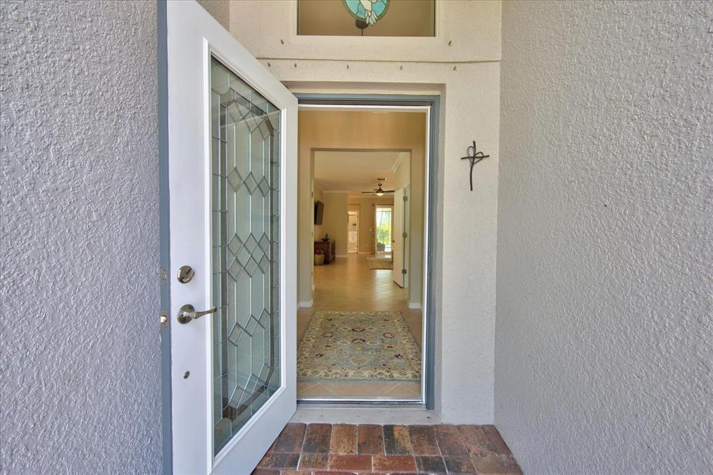 An open front door reveals an entryway leading into a home with tiled floors — 7031 QUIET CREEK DRIVE, BRADENTON, FL