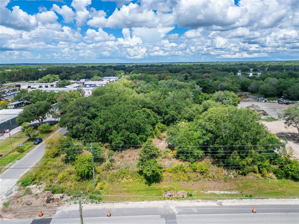 An aerial view shows a vacant, tree-covered lot situated between a road and industrial buildings — TURKEY CREEK ROAD, PLANT CITY, FL