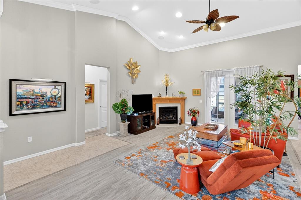 A living room features a fireplace, vaulted ceilings, orange furniture, and a patterned area rug — 19562 SW 84TH PLACE, DUNNELLON, FL