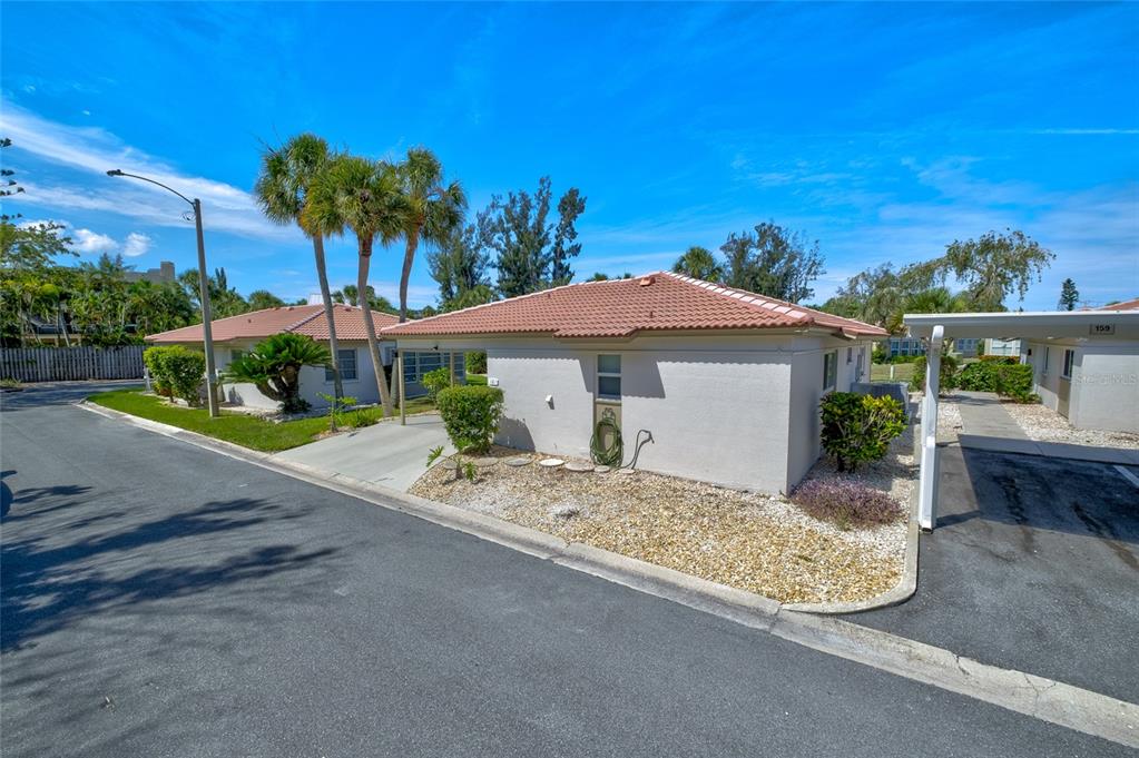 A single-story house with a tiled roof and a carport sits on a corner lot — 161 VISTA HERMOSA CIRCLE UNIT 26A, SARASOTA, FL